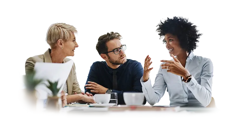 Três profissionais em uma reunião de trabalho sentados à mesa, com uma mulher gesticulando enquanto explica algo e dois colegas ouvindo atentamente, em um ambiente corporativo.